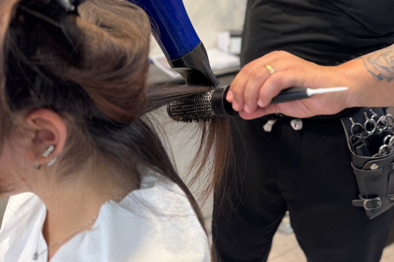 Donna seduta su una sedia che si fa fare i capelli da un parrucchiere